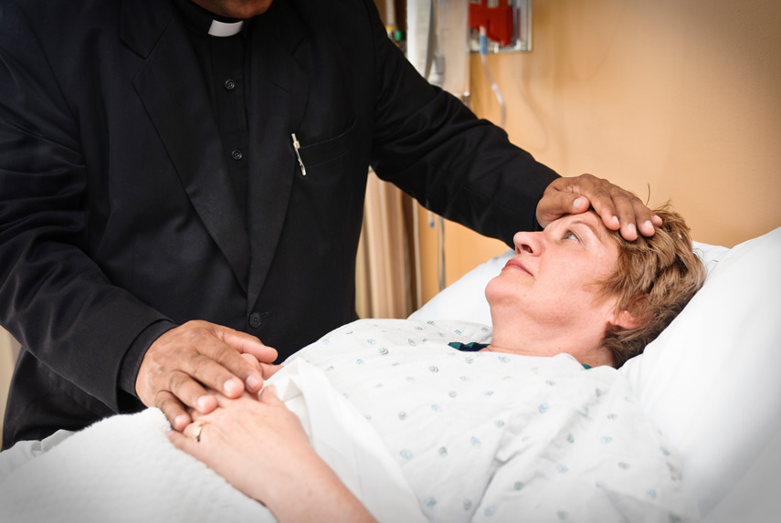 Hospice-patient-receiving-spiritual-care-from-chaplain-in-black-suit