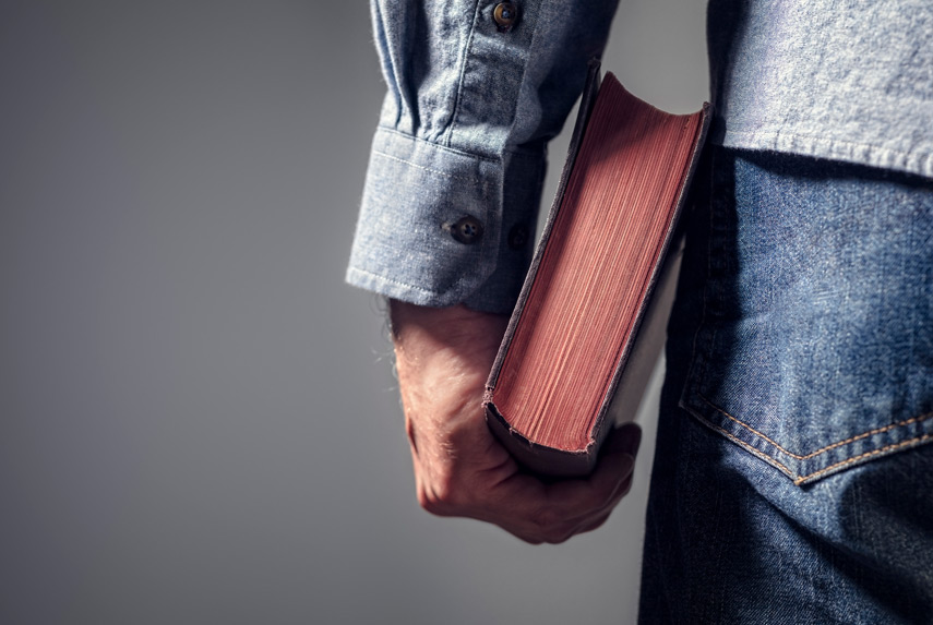 Man-holding-Bible-on-gray-background